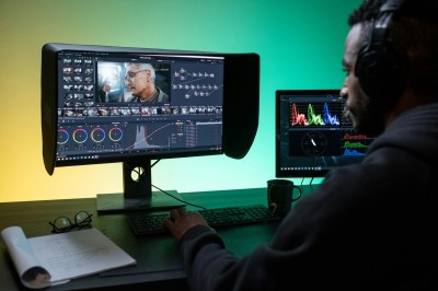 Man with headphones on sitting in front of an editing system